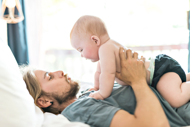 Dad in bed with baby on his chest