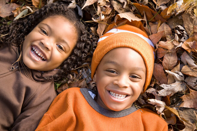 Little girl and boy laughing on leaves