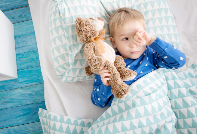 Child holding a teddy bear in bed